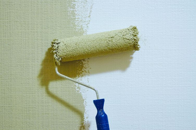 paint roller with green paint on wall