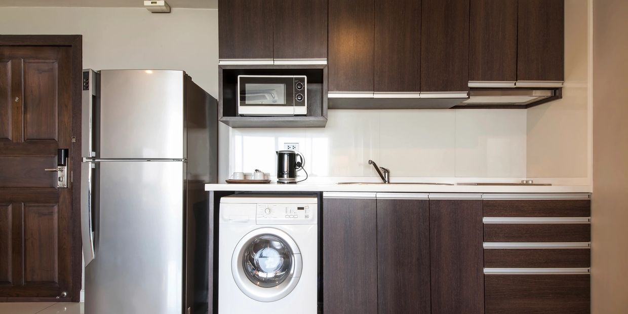 Urban Kitchen with refrigerator, countertop microwave, cooktop and combo washer.
