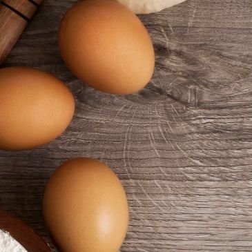 Three brown eggs on a wooden surface.