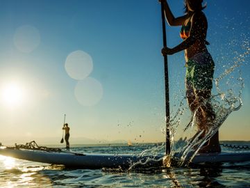 person on a paddle board the splashing water with a paddle