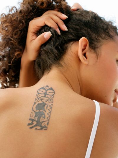 Woman showing tattoo on back of neck for laser tattoo removal at FreedomMD LUXE Saco Portland Maine