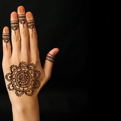 Hand adorned with intricate henna designs on fingers and back.