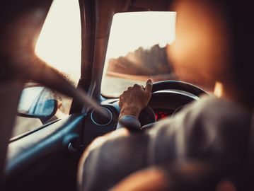 Shot from inside a car with a sunset and a lady driving