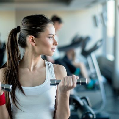 A woman lifting dumbbells in a gym, focused on her workout.