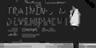 A businessman standing in front of a blackboard with words written on it.