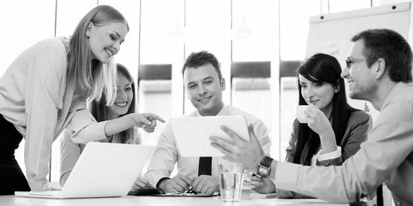 A group of professionals collaborating around a tablet during a meeting.