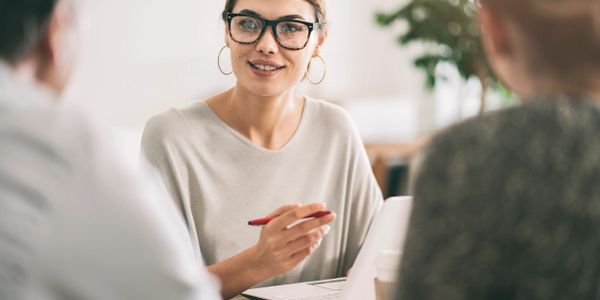 Woman with glasses on a laptop talking to a couple about finances