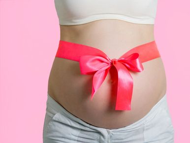 Pregnant belly with pink ribbon tied in a bow.