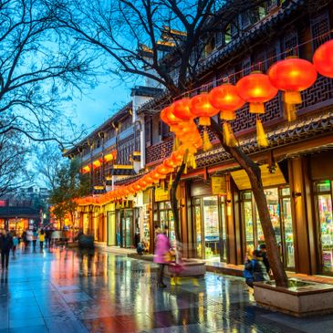 Street decorated with glowing red lanterns at dusk in a traditional setting.