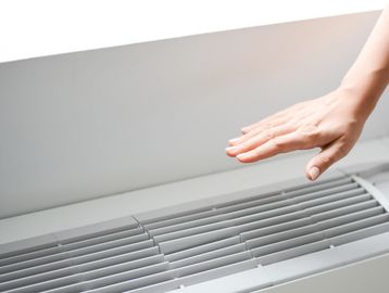 Hand warming near an air conditioner vent.