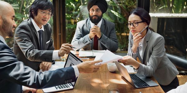 multicultural group of people working  together at a table 