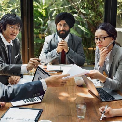 Diverse professionals discussing documents in a meeting room with laptops.