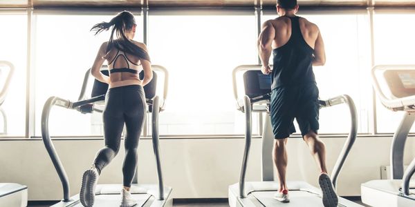 Man and woman running on separate treadmills.