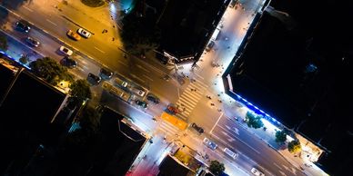 Nighttime aerial view of a busy urban intersection with cars and pedestrians.