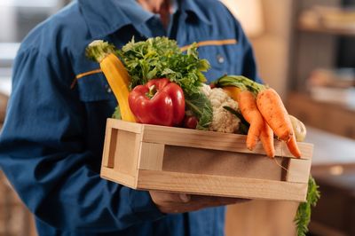 Man holding wooden box with vegetables in it