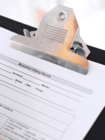 Clipboard containing white paper with the text "Medication History Record" written.