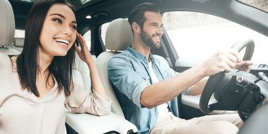 a man and woman driving happily in their car