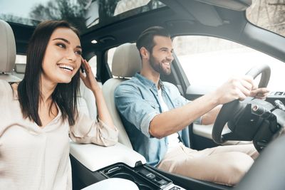 A happy couple driving in a car on a sunny day