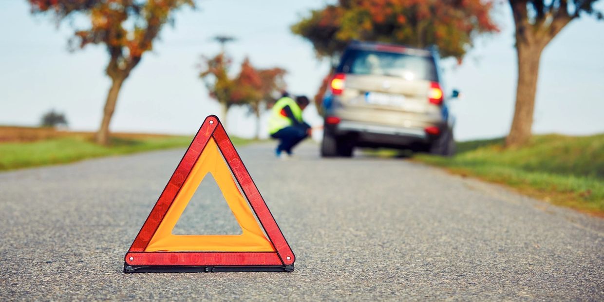 Road hazard sign warning of disabled vehicle on the side of the road