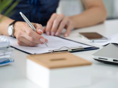 Une personne signe un document sur un bureau.