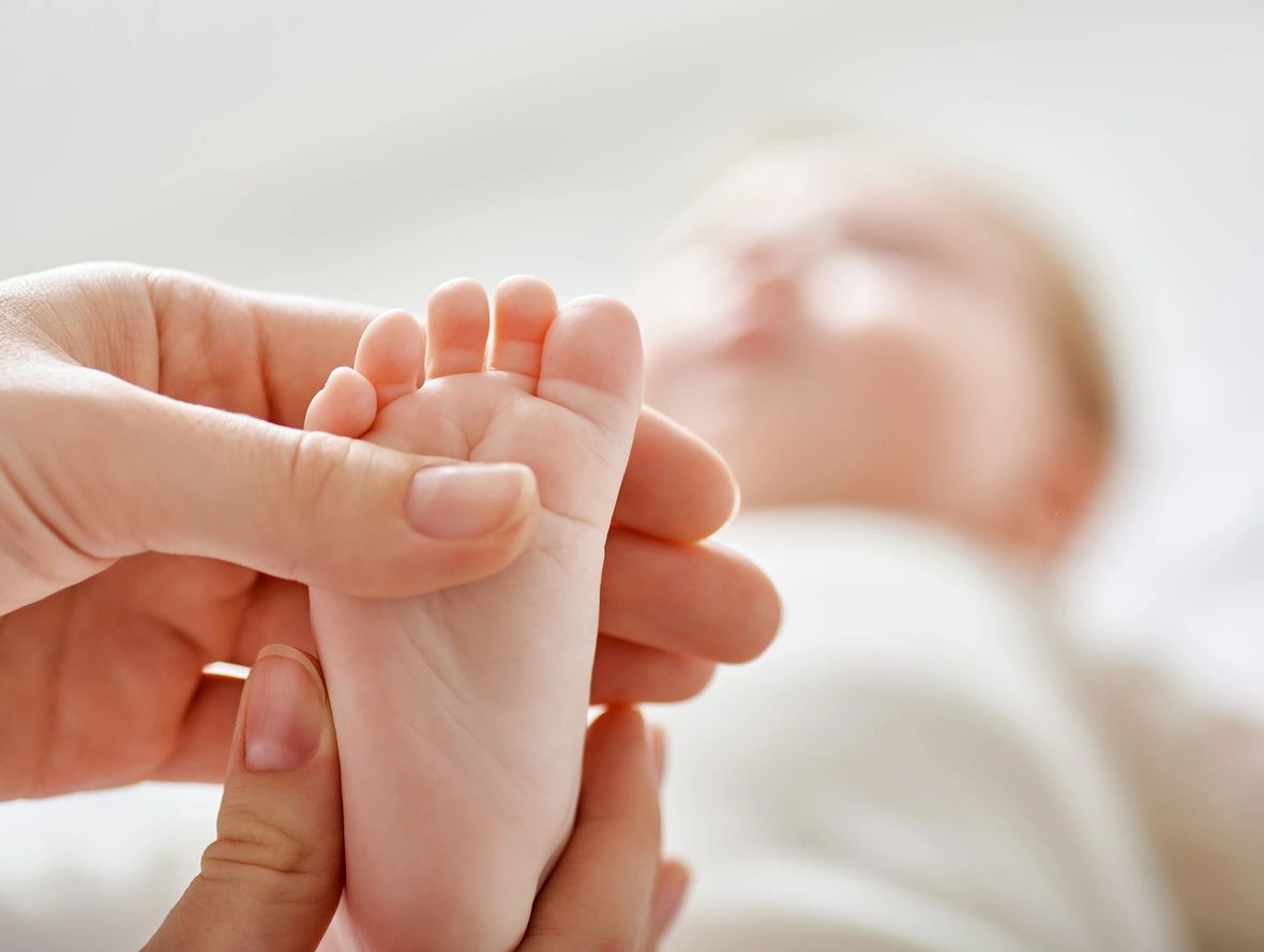 A baby having its foot massaged.