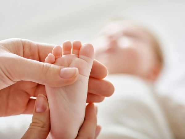 Close-up of an adult gently holding a baby's foot.