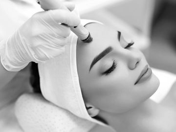 Woman receiving a facial treatment with a handheld device.