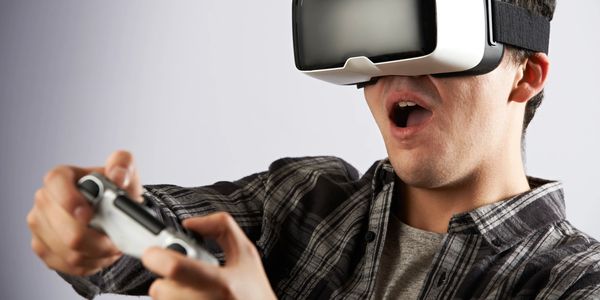 Young man immersed in VR gaming, holding a controller with excitement.