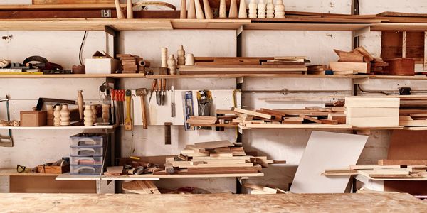 Shelves in a wodworking shop, filled with wood, plywood, dowels, and woodworking tools