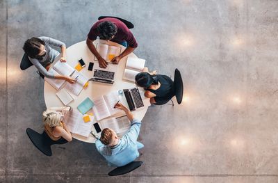 bird's eye view of five people sitting and working at a round table