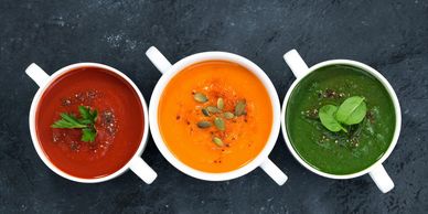 Tomato soup in a white bowl, pumpkin soup in a white bowl, spinach soup in a white bowl