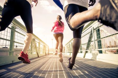 Three people running on a bridge during sunrise or sunset.
