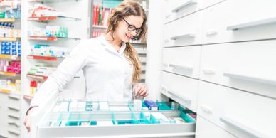 Persian female pharmacy assistant grabbing the medication from cabinet drawer
