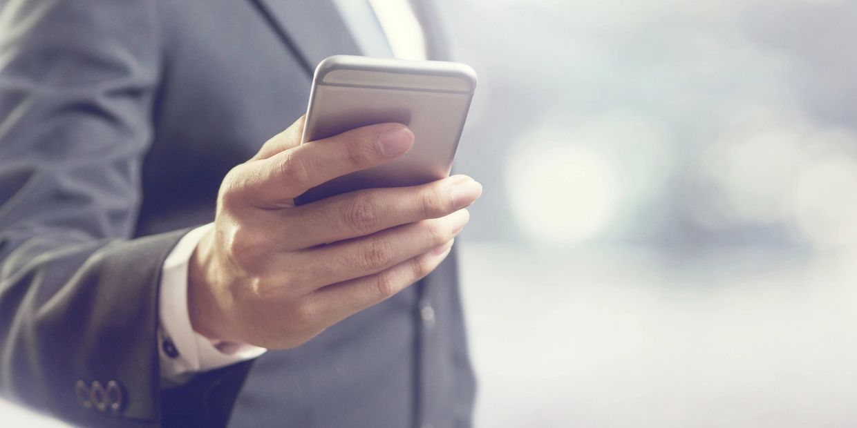 Businessman in suit using smartphone with blurred background.