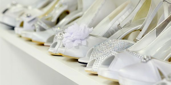 A row of elegant white bridal shoes with various decorative designs.