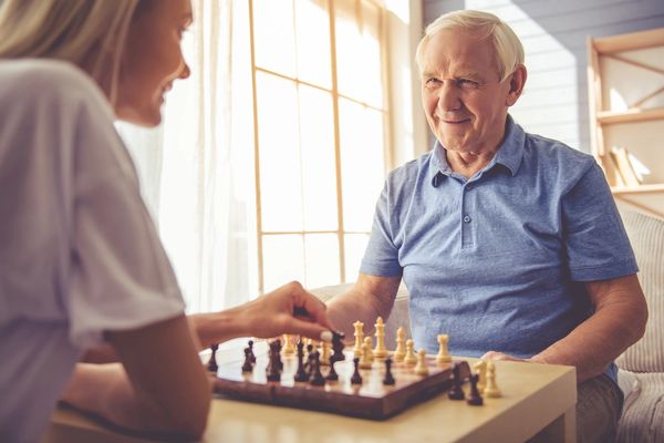 two elderly people sitting across from each other and playing chess