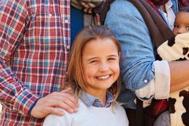 Smiling young girl with family members around her.