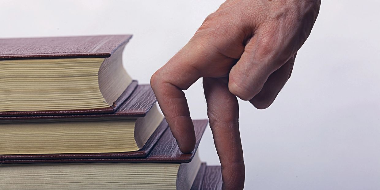Fingers walking on stair-stepped books to indicate progression, moving up.