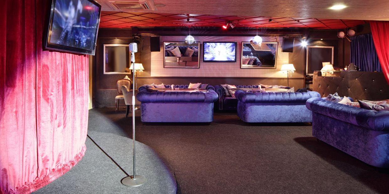 Cozy lounge with velvet couches, a microphone, and red curtains for performances.