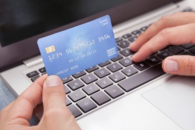 Person holding a credit card in front of their laptop