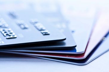 A close-up of stacked credit cards on a white surface.