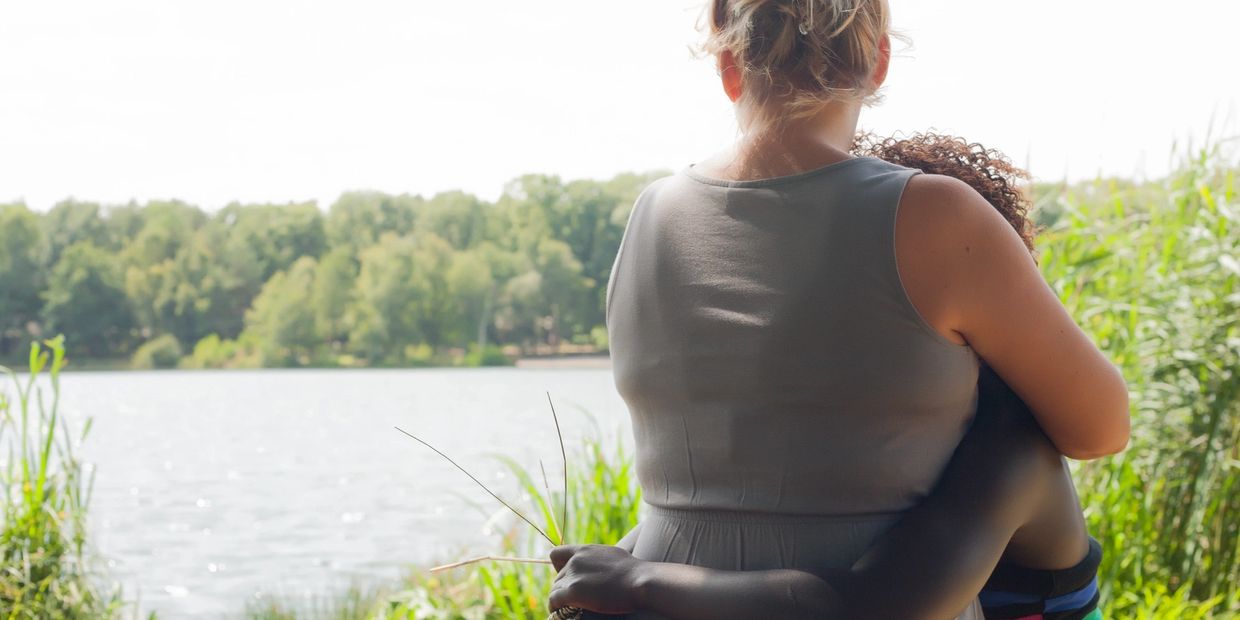 Two people embracing by a lakeside.