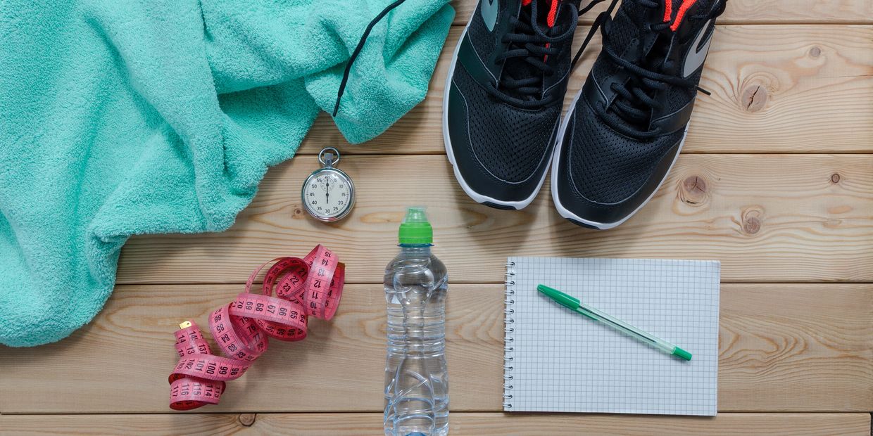running shoes, measuring tape, and water bottle on a wooden surface