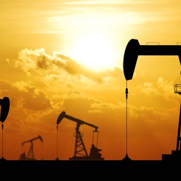 Oil pump jacks silhouetted against a sunset.