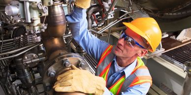 worker in protective gear working on large machine