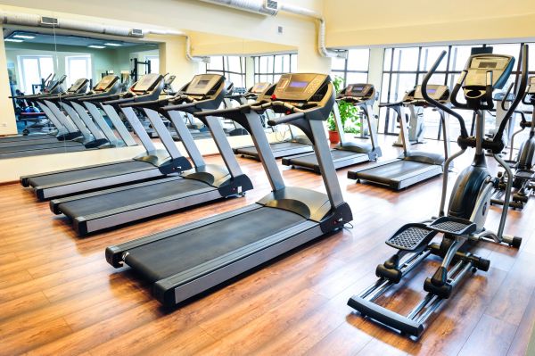 Row of treadmills and exercise machines in gym.