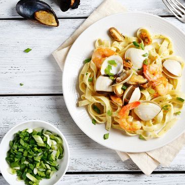 Seafood pasta with shrimp, clams, and mussels on a white plate.