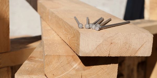 Stack of wooden planks with nails on top.