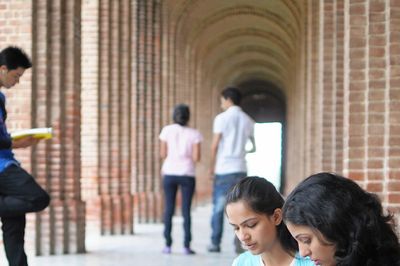 Students studying and walking in a brick-arched corridor.
