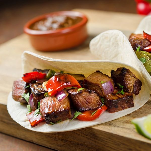 Grilled steak taco with peppers and onions in a soft tortilla.